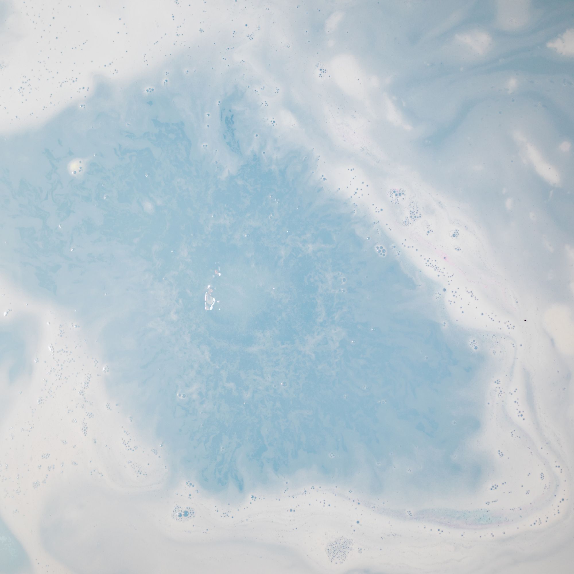 Mineral bath soak dispersing in water, representing a calming at-home recovery ritual to relax muscles and extend massage benefits.